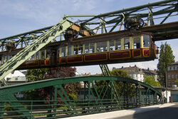 Kaiserwagen der Schwebebahn über einer Brücke mit grünem Stahlgeländer
