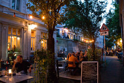 Blick ins Luisenviertel: Menschen sitzen im Sommer an Tischen vor einem Restaurant
