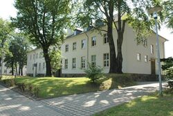 Campus Freudenberg, großes weißes Gebäude mit Bäumen und Rasen im Vordergrund