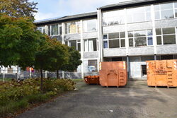 Vor der ehemaligen Justzivollzugsschule stehen orangefarbenen Container