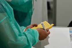 Eine Person im Schutzkittel hält einen Impfpass in der Hand
