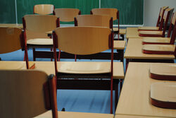 Blick in ein Klassenzimmer mit Tafel und hochgestellten Stühlen auf Tischen