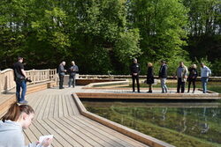 Bei einem Pressetermin stehen Menschen auf Stegen am neuen Teich der Station Natur und Umwelt
