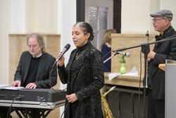 Die drei Musiker auf der Bühne, am Piano, mit Mikrofon und Klarinette, alle in schwarz gekleidet