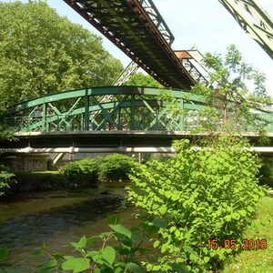 grüne Stahlbogenbrücke im Grünen über Wupper, unter Schwebebahn