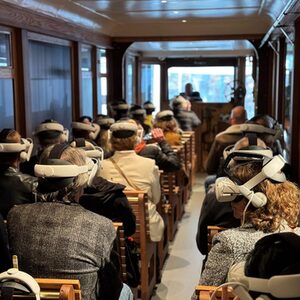 Besucher mit VR-Brillen sitzen in einem alten Kaiserwagen im Schwebodrom