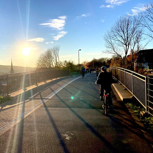 Fahrradfahrer sind im Sonnenuntergang auf der Nordbahntrasse unterwegs.