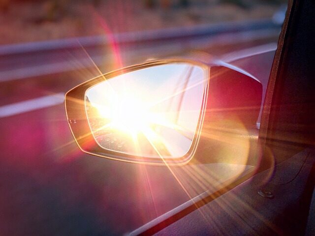 Im Außenspiegel eines Autos spiegelt sich die Sonne