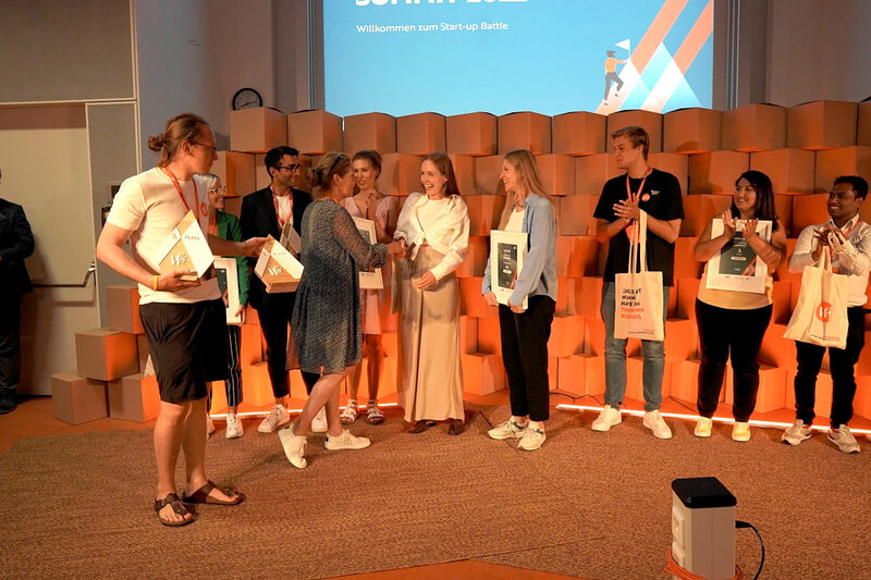 Antje Lieser überreicht den Gründerinnen von Herbsom die Gewinnerurkunde.