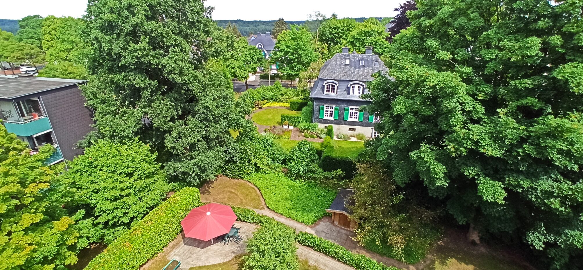 Blick von oben in einen Garten und Häuser im Hintergrund
