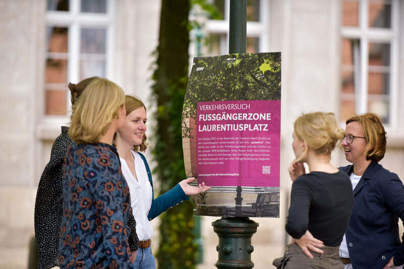 Menschen schauen sich Poster zum Verkehrsversuch am Laurentiusplatz an