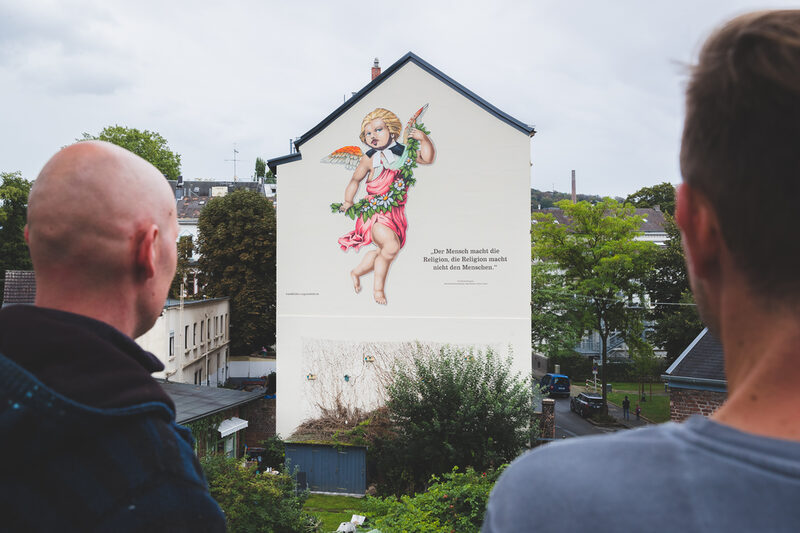 Die beiden Künstler Martin Heuwold und Kolja Kunstreich vor ihrem ersten Engels-Wandbild "Zweifel" in der Gutenbergstraße im Stadtteil Arrenberg.