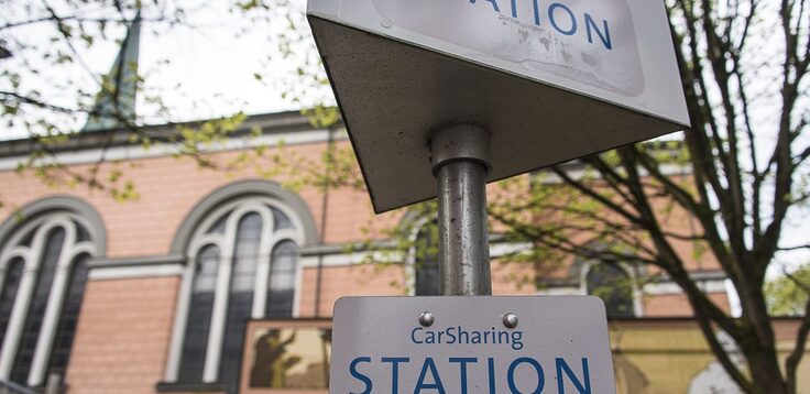 Das Schild einer CarSharing-Station vor einer Kirche
