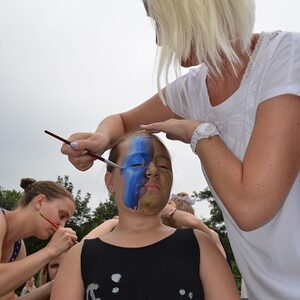 132 3.Woche 2015 Mitarbeiterin schminkt Mädchen blaue Gesichtshälfte