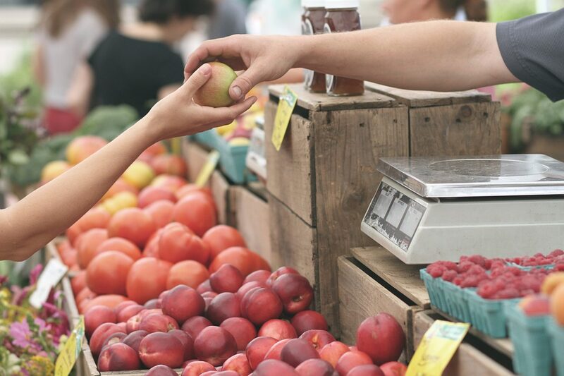 Ein Obsthändler überreicht einen Apfel
