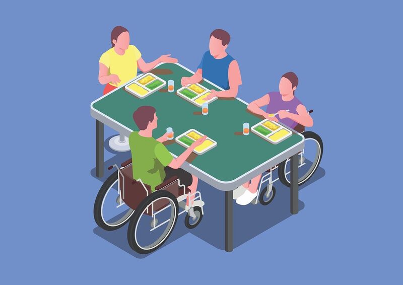 Vier Personen, zwei davon im Rollstuhl, sitzen an einem Tisch und Essen gemeinsam.