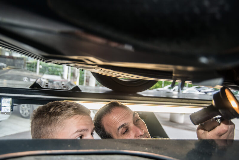 Ein Schüler und ein Fachmann untersuchen ein Auto