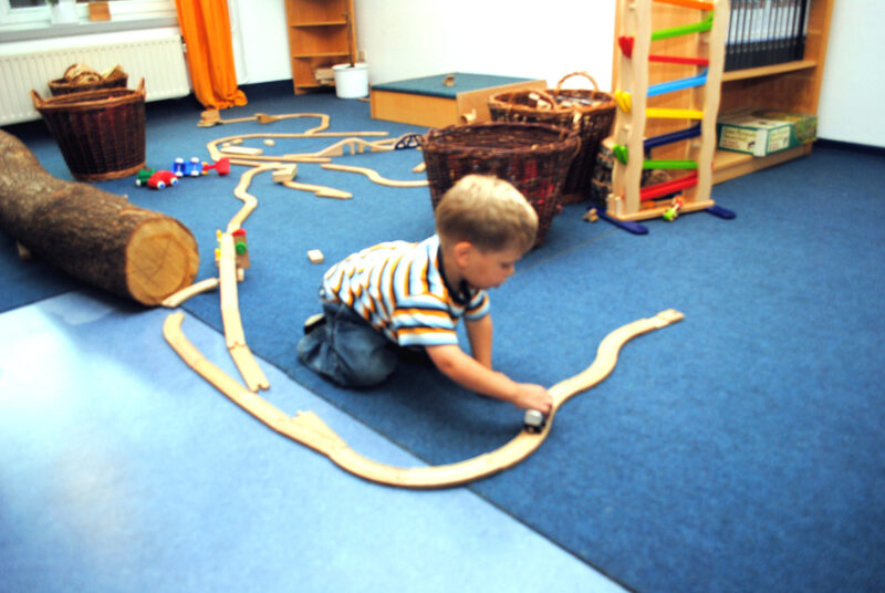 Junge in Kindertageseinrichtung spielt mit Spielzeugeisenbahn
