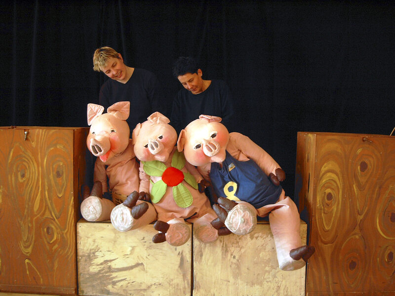Zwei Schauspielerinnen mit drei großen Schweinepuppen