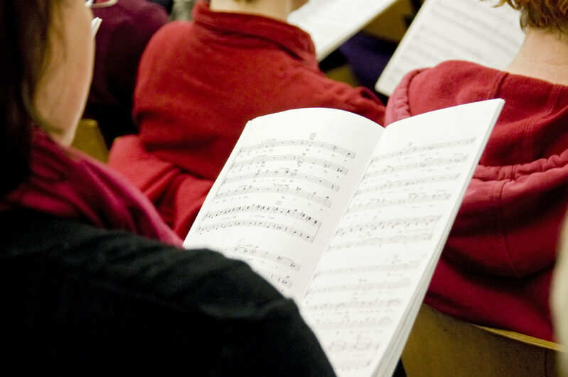 Blick über die Schulter eines Chormitglieds auf ein Text- un dNotenblatt