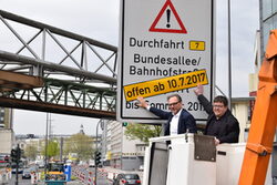 Oberbürgermeister Andreas Mucke und Verkehrsdezernennt Frank Meyer kleben den Zusatz auf das alte Hinweisschild