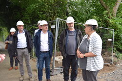Oberbürgermeister Andreas Mucke und Beteiligte mit Bauhelm auf der Baustelle