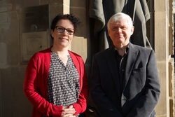 Sandra Heinen und Erwin Petrauskas stehen vor eine Steinwand in der Sonne
