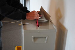 Ein Wahlumschlag wird in eine Wahlurne geworfen