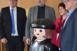 Luther als übergroße Playmobil-Figur mit dem Oberbürgermeister, der Superintendentin, dem Stadtdirektor und einem Vertreter der Landeskirche