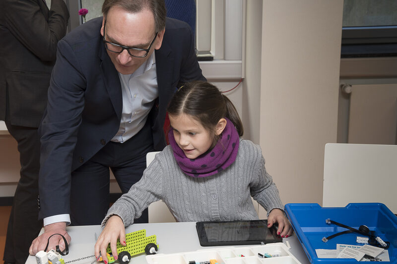Oberbürgermeister Andreas Mucke und ein Mädchen probieren die neuen technischen Möglichkeiten im LearnLab aus