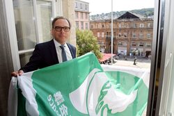 Oberbürgermeister Andreas Mucke mit der Flagge in der Hand vorm offenen Rathaus-Fenster