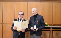 Oberbürgermeister Mucke mit Amtskette verliest Peter Engelmann die Verleihungsurkunde