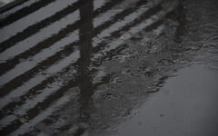 Regenpfütze mit Tropfen auf Asphalt - Nahaufnahme