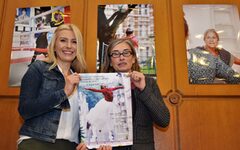 Jana-Sophia Ihle (links, Vorsitzende des Beiratsfür das Mirker Quartier) und Inge Grau (Mitglied des Organisationsteams des Forum:Mirke) halten ein Plakat für die Fotoausstellung "FACEtten der Mirke" in die Kamera