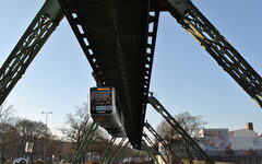 Neuer hellblauer Schwebebahnzug von vorne, Gerüst.