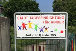 Schild mit Schriftzug: "Städt. Tageseinrichtung für Kinder" und bunten Kinderfiguren