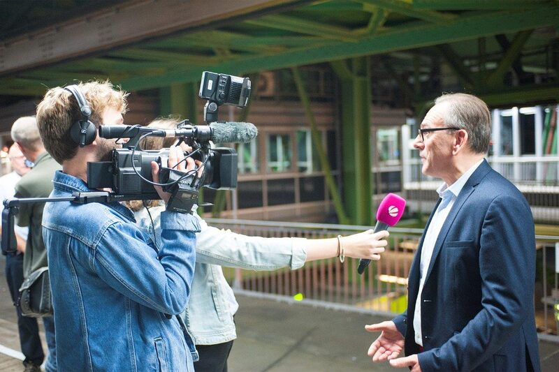 Oberbürgermeister Andreas Mucke wird auf dem Bahnsteig von einem Fernsehteam interviewt.