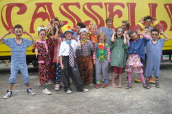 Als Clowns verkleidete Kinder vor dem Schriftzug des Zirkus Casselly