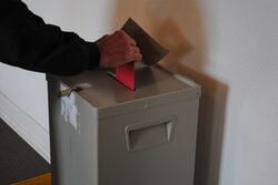Ein Stimmzettel wird in die Wahlurne geworfen