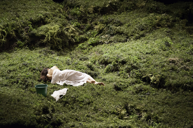 Szene aus dem Tanztheaterstück "Wiesenland" - Tänzerin liegt mit einem weißen Laken bedeckt in grüner Wiese