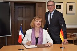 Auf dem Foto sitzt die französische Generalkonsulin Dr. Olivia Berkeley-Christmann an einem Tisch im Büro des Oberbürgermeisters, Andreas Mucke steht daneben.