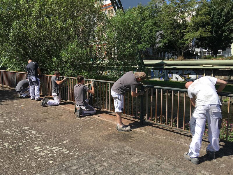 Azubis des Ausbildungsprojektes Ufer streichen das Geländer am Wupperufer am Alten Markt