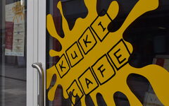 Die Eingangstür zum neuen Café ziert ein gelber Fleck mit der Aufschrift "Kuki Café"