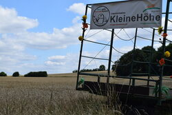 Landschaftsbild mit Getreidefeldern und Protestplakat im Vordergrund