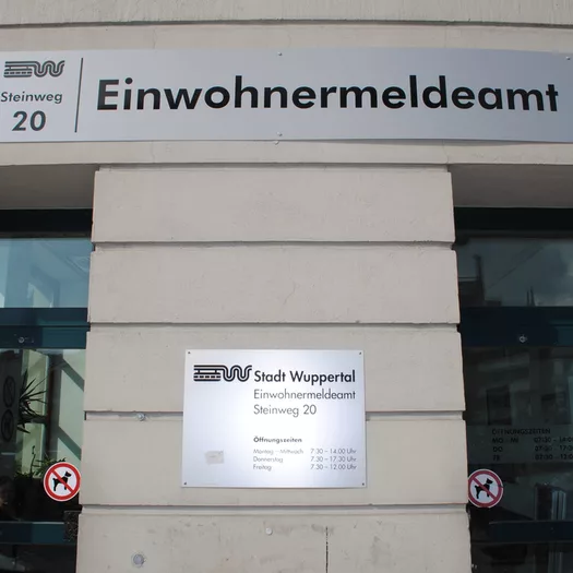 Das Einwohnermeldeamt von außen, das große Schild und zwei Türen sichtbar
