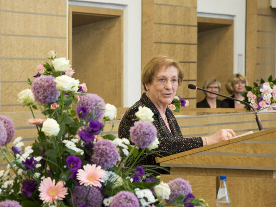 Ursula Kraus am Rednerpult des Ratssaales mit Blumengesteck im Vordergrund