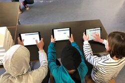 Drei Schüler halten ein Tablet in der Hand