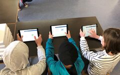 Drei Schüler halten ein Tablet in der Hand