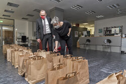 Oberbürgermeister Andreas Mucke und Bibliotheks-Mitarbeiterin mit gepackten Bücher-Taschen für Selbstabholer