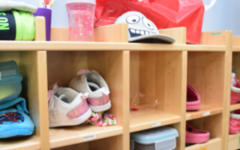 Ein Regal im Kinderaten mit Zahnputzbecher, Schuhen, einer Dose und einer Kappe